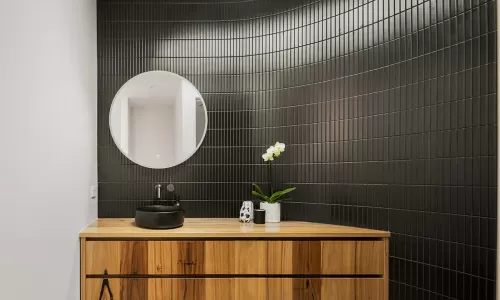 A modern bathroom with a wooden vanity and round mirror