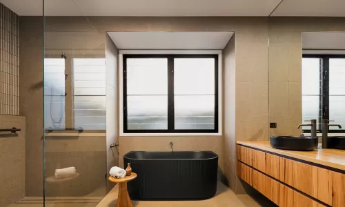 A modern bathroom with a large window and a black freestanding bathtub