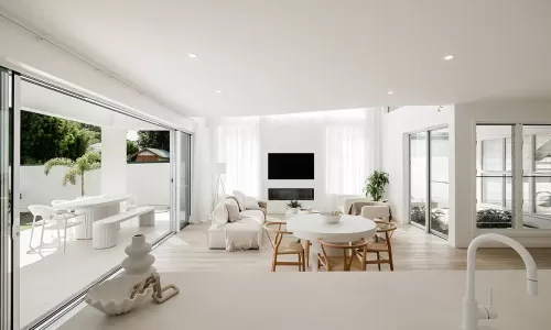 A modern, minimalist living room with white walls, furniture, and sheer curtains