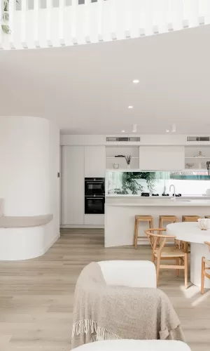 A modern kitchen with white walls, wooden flooring, and a built-in oven