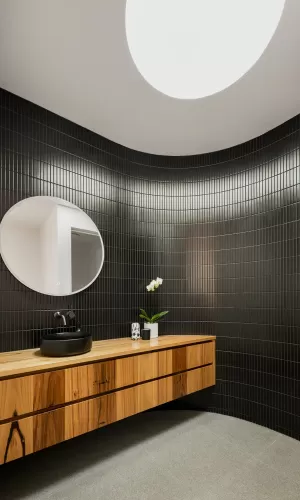 A modern bathroom with a round mirror and skylight