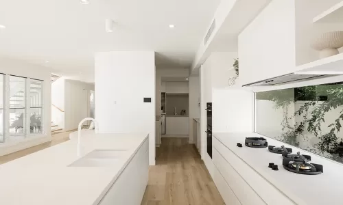 A modern kitchen with white cabinets, a kitchen island with a sink, and a gas stove top
