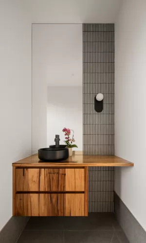 modern bathroom with a wooden vanity and black countertop sink with a wall-mounted mirror