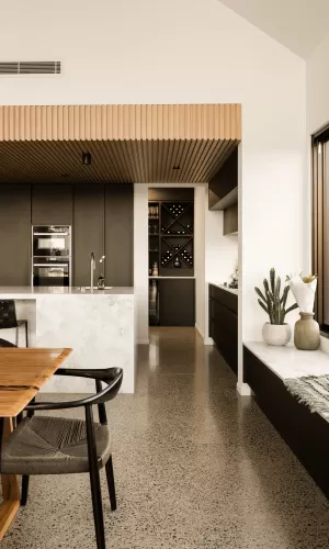 Modern kitchen with black cabinets, marble island, wine storage, and large window with plants