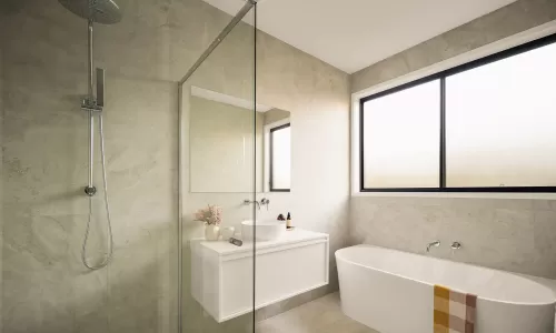 Modern bathroom with a glass-enclosed shower, white vanity, freestanding bathtub, and large window