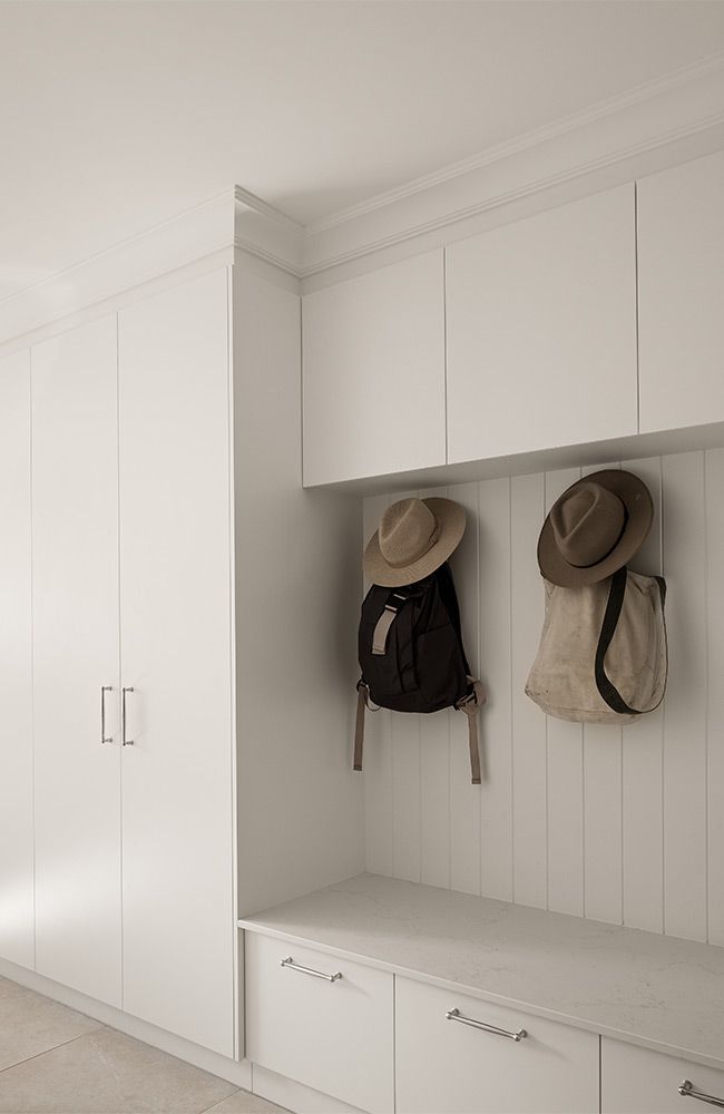 shows a minimalist white mudroom or entryway storage area.