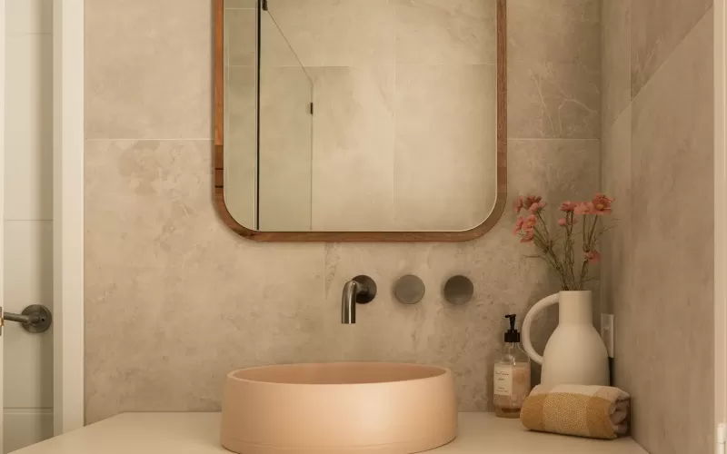 Modern bathroom with a wooden vanity, large mirror, beige round sink, and decorative flowers in a vase