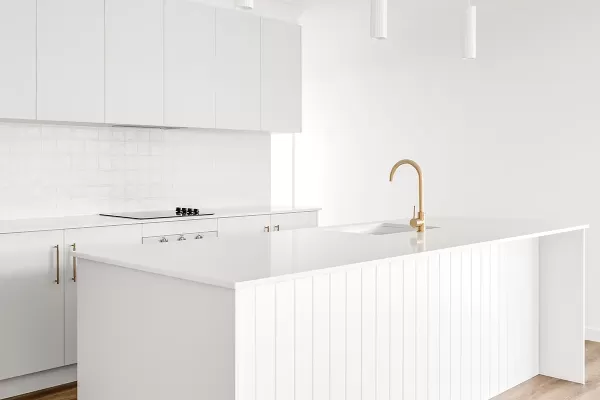 A white kitchen with a white island and wood floor