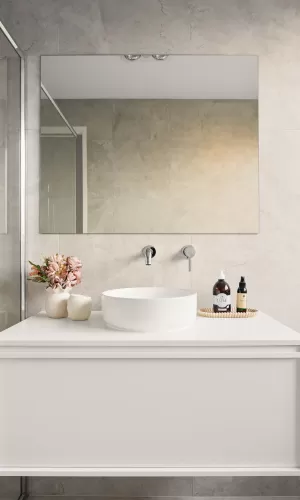 Modern bathroom with a round sink, large mirror, flowers in a vase, and toiletries on the counter