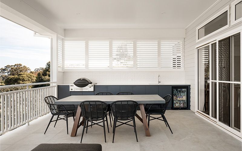 Six black rattan-style chairs around the table