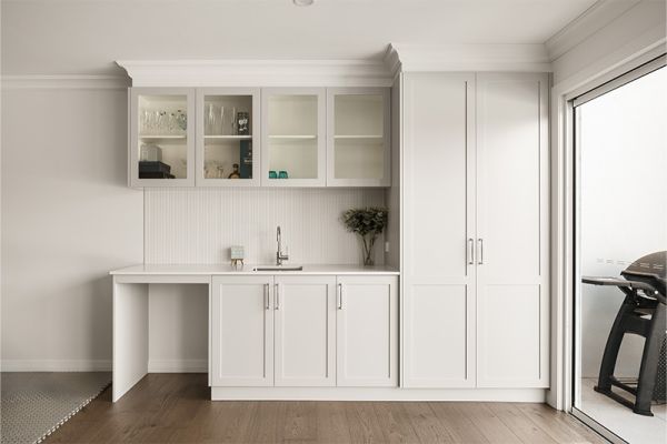 Clean white butler's pantry with glass-front cabinets and outdoor access.